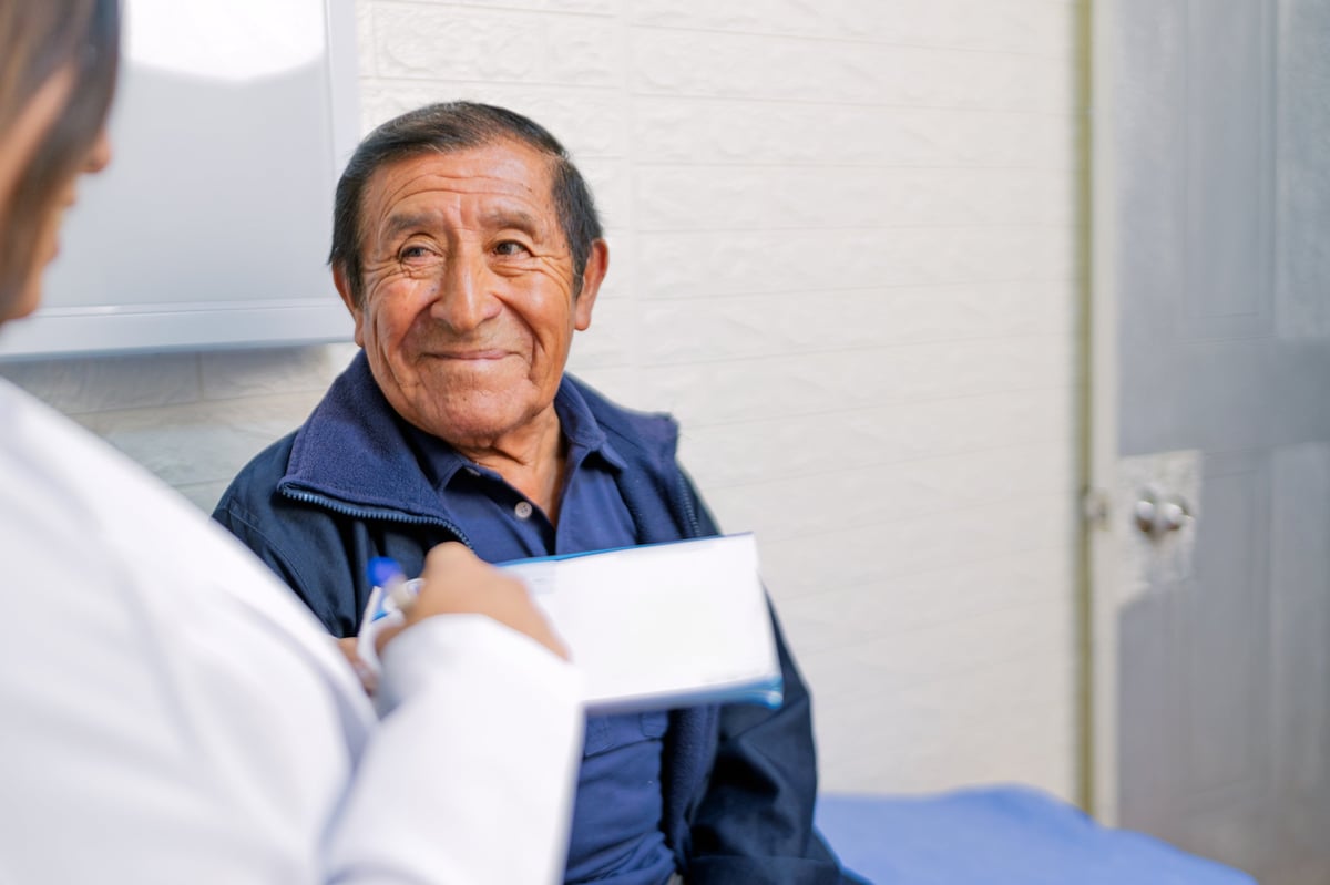 Senior man discussing medical prescription with doctor during consultation in a medical office, highlighting the importance of healthcare communication