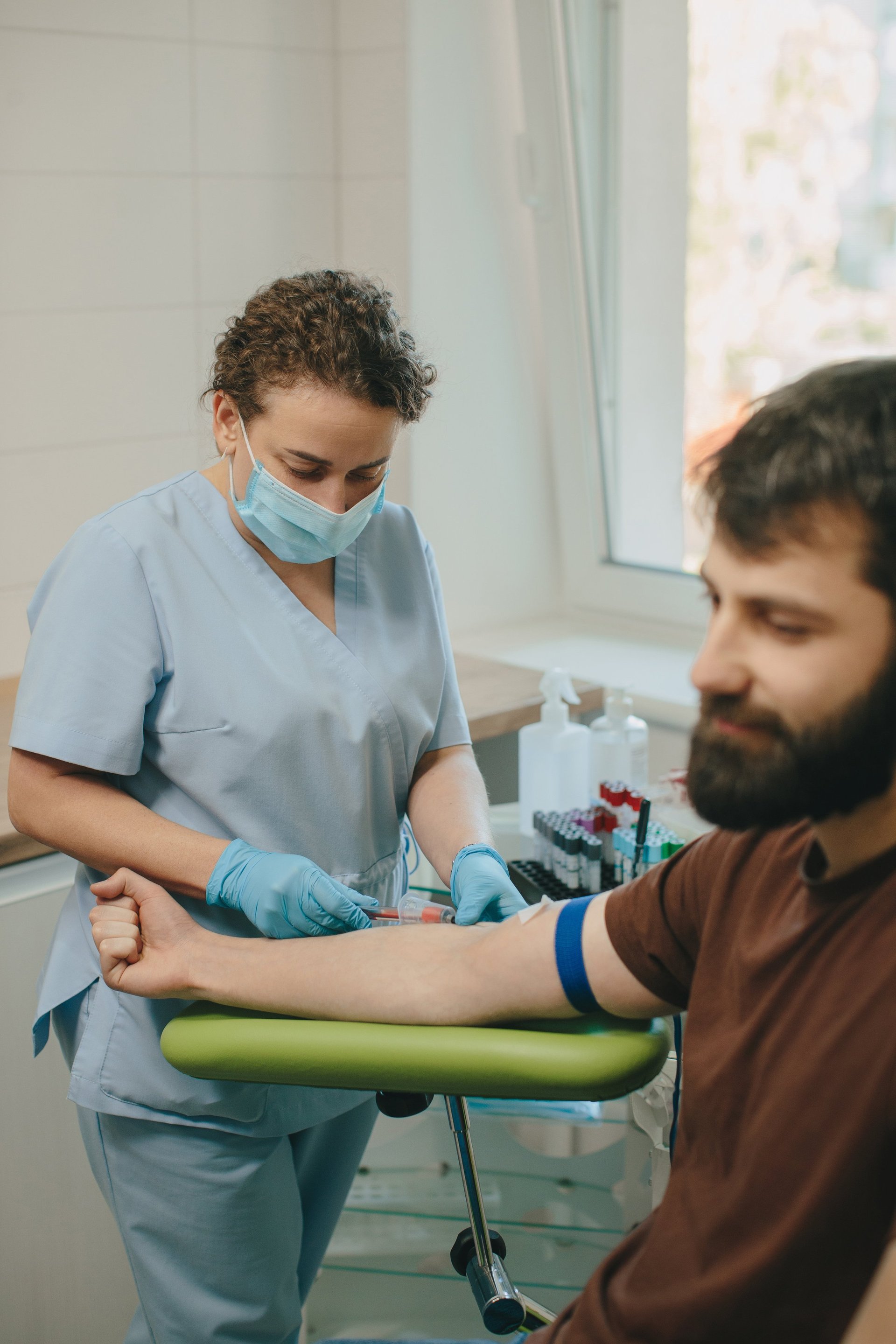 Medical professional taking a blood sample from male patient in a clinic